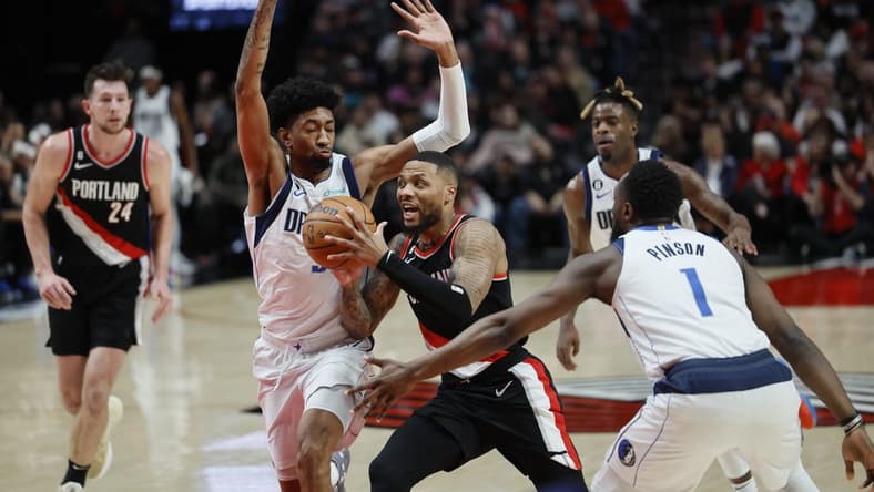 Jan 15, 2023; Portland, Oregon, USA; Portland Trail Blazers point guard Damian Lillard (0) drives for the basket between Dallas Mavericks forward Christian Wood (35, left) and guard Theo Pinson (1) during the first half at Moda Center. Mandatory Credit: Soobum Im-USA TODAY Sports