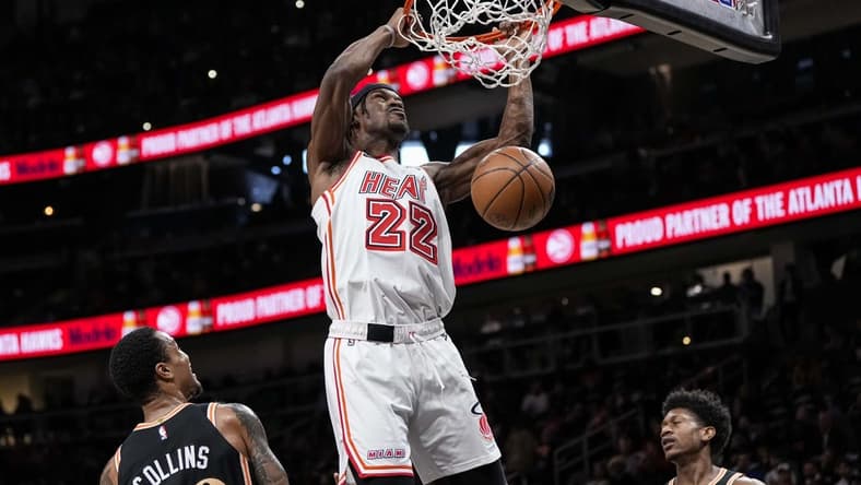 Jan 16, 2023; Atlanta, Georgia, USA; Miami Heat forward Jimmy Butler (22) dunks between Atlanta Hawks forwards John Collins (20) and  De'Andre Hunter (12) during the first half at State Farm Arena. Mandatory Credit: Dale Zanine-USA TODAY Sports