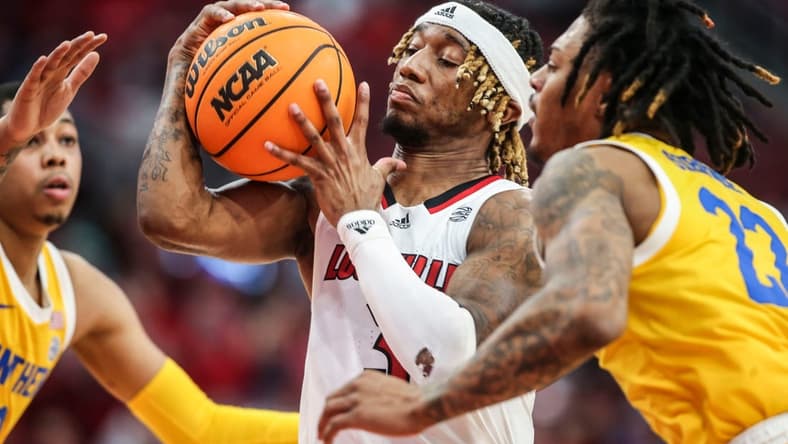 Louisville's El Ellis drives between Pitt guard Greg Elliott, left, and Pitt guard Nike Sibande in the second half. The Cards lost 75-54 to the visiting Panthers.  Jan. 18, 2023

Louisville Vs Pitt Jan 18 2023