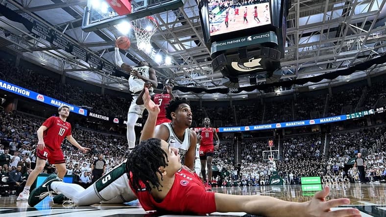 Jan 19, 2023; East Lansing, Michigan, USA; In the foreground, Rutgers Scarlet Knights guard Derek Simpson (0) and Michigan State Spartans guard A.J. Hoggard (11) wait for the verdict from the referee after a collision under the basket in the second half at Jack Breslin Student Events Center. Rutgers Scarlet Knights guard Derek Simpson (0) was called on a blocking foul. Mandatory Credit: Dale Young-USA TODAY Sports