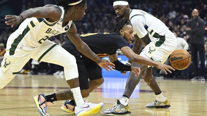 Jan 21, 2023; Cleveland, Ohio, USA; Cleveland Cavaliers guard Darius Garland (10) dribbles between Milwaukee Bucks guard Jrue Holiday (21) and forward Bobby Portis (9) in the second quarter at Rocket Mortgage FieldHouse. Mandatory Credit: David Richard-USA TODAY Sports