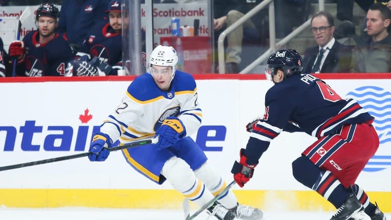 Jan 26, 2023; Winnipeg, Manitoba, CAN; Buffalo Sabres forward Jack Quinn (22) tries to skate away from Winnipeg Jets defenseman Neal Pionk (4) during the first period at Canada Life Centre. Mandatory Credit: Terrence Lee-USA TODAY Sports