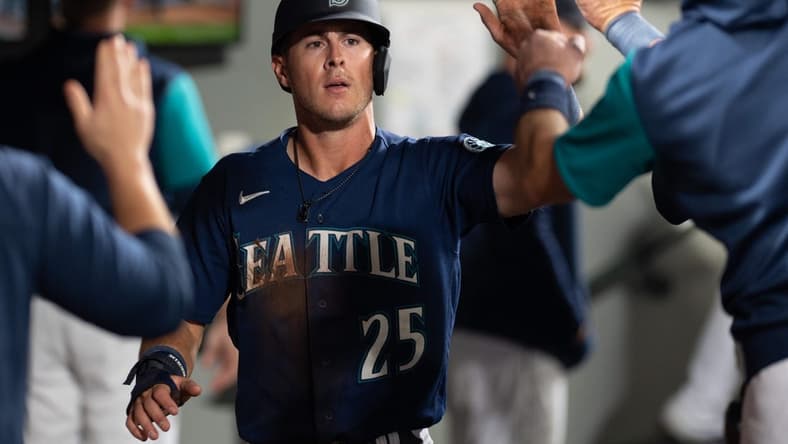 Oct 3, 2022; Seattle, Washington, USA; Seattle Mariners right fielder Dylan Moore (25) celebrates in the dugout after scoring a run against the Detroit Tigers during the fifth inning at T-Mobile Park. Mandatory Credit: Steven Bisig-USA TODAY Sports