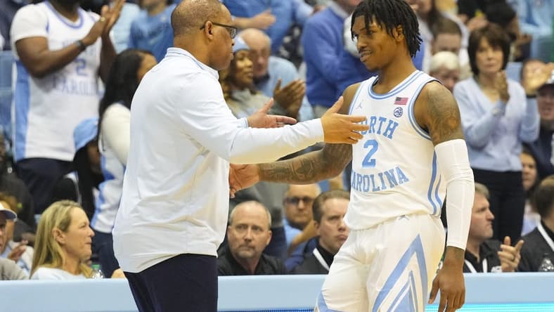 Jan 7, 2023; Chapel Hill, North Carolina, USA; North Carolina Tar Heels coach Hubert Davis greets guard Caleb Love (2) after he come out of the game against the Notre Dame Fighting Irish during the second half at Dean E. Smith Center. Mandatory Credit: James Guillory-USA TODAY Sports