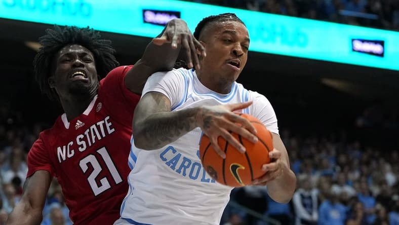 Jan 21, 2023; Chapel Hill, North Carolina, USA; North Carolina Tar Heels forward Armando Bacot (5) grabs a rebound as North Carolina State Wolfpack forward Ebenezer Dowuona (21) defends in the first half at Dean E. Smith Center. Mandatory Credit: Bob Donnan-USA TODAY Sports