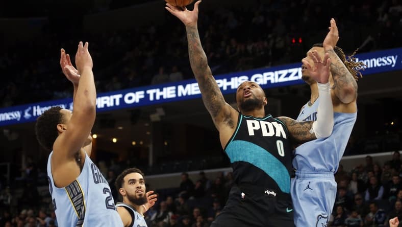 Feb 1, 2023; Memphis, Tennessee, USA; Portland Trail Blazers guard Damian Lillard (0) moves to the basket as Memphis Grizzlies guard Desmond Bane (22) and Memphis Grizzlies forward Brandon Clark (15) defend during the first half at FedExForum. Mandatory Credit: Petre Thomas-USA TODAY Sports