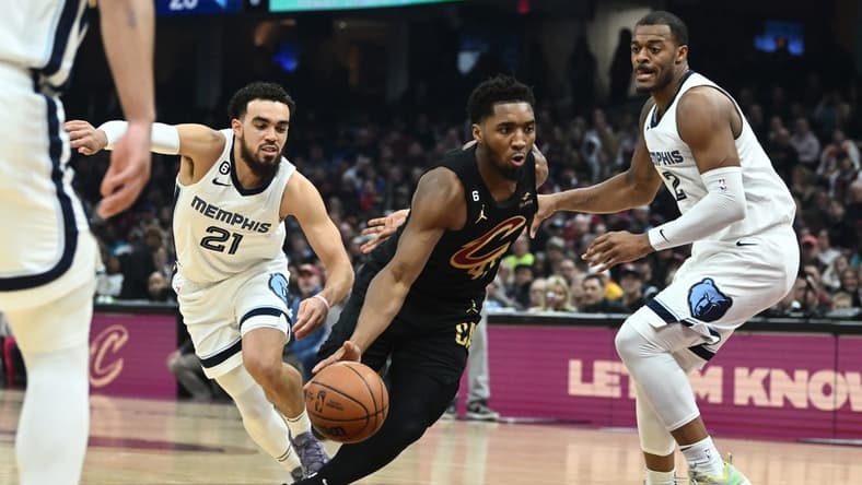 Feb 2, 2023; Cleveland, Ohio, USA; Cleveland Cavaliers guard Donovan Mitchell (45) drives to the basket between Memphis Grizzlies guard Tyus Jones (21) and forward Xavier Tillman (2) during the first half at Rocket Mortgage FieldHouse. Mandatory Credit: Ken Blaze-USA TODAY Sports