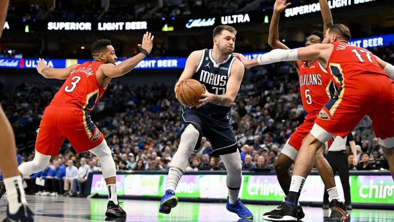 Feb 2, 2023; Dallas, Texas, USA; Dallas Mavericks guard Luka Doncic (77) drives to the basket past New Orleans Pelicans guard CJ McCollum (3) and forward Herbert Jones (5) and center Jonas Valanciunas (17) during the first quarter at the American Airlines Center. Mandatory Credit: Jerome Miron-USA TODAY Sports