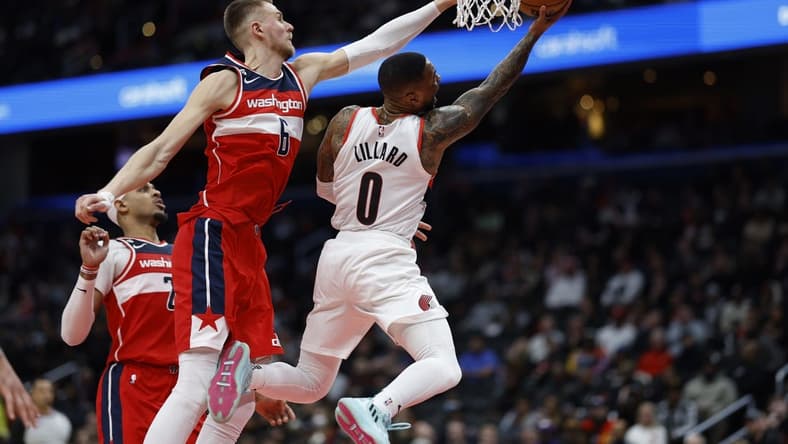 Feb 3, 2023; Washington, District of Columbia, USA; Portland Trail Blazers guard Damian Lillard (0) shoots the ball as Washington Wizards center Kristaps Porzingis (6) defends in the second quarter at Capital One Arena. Mandatory Credit: Geoff Burke-USA TODAY Sports