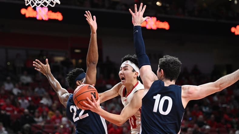 Feb 5, 2023; Lincoln, Nebraska, USA; Nebraska Cornhuskers guard Keisei Tominaga (30) drives between Penn State Nittany Lions guard Jalen Pickett (22) and guard Andrew Funk (10) in the first half at Pinnacle Bank Arena. Mandatory Credit: Steven Branscombe-USA TODAY Sports