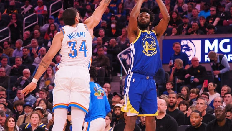 Feb 6, 2023; San Francisco, California, USA; Golden State Warriors small forward Andrew Wiggins (22) scores a three point basket against Oklahoma City Thunder shooting guard Kenrich Williams (34) during the second quarter at Chase Center. Mandatory Credit: Kelley L Cox-USA TODAY Sports