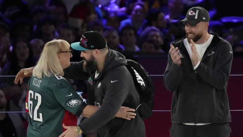 Feb 6, 2023; Phoenix, AZ, USA; Donna Kelce hugs her son Philadelphia Eagles center Jason Kelce (62) while her other son Kansas City Chiefs tight end Travis Kelce (87) claps during Super Bowl Opening Night at Footprint Center. Mandatory Credit: Cheryl Evans-USA TODAY Sports