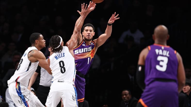 Feb 7, 2023; Brooklyn, New York, USA; Phoenix Suns guard Devin Booker (1) passes the ball to guard Chris Paul (3) as Brooklyn Nets guard Patty Mills (8) and center Nic Claxton (33) defend during the first half at Barclays Center. Mandatory Credit: Vincent Carchietta-USA TODAY Sports