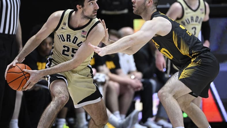 Feb 9, 2023; West Lafayette, Indiana, USA; Purdue Boilermakers guard Ethan Morton (25) keeps the ball away from Iowa Hawkeyes guard Connor McCaffery (30) during the first half at Mackey Arena. Mandatory Credit: Marc Lebryk-USA TODAY Sports