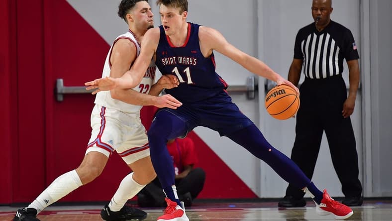 Feb 9, 2023; Los Angeles, California, USA; St. Mary's Gaels center Mitchell Saxen (11) moves the ball against Loyola Marymount Lions forward Alex Merkviladze (23) during the first half at Gersten Pavilion. Mandatory Credit: Gary A. Vasquez-USA TODAY Sports