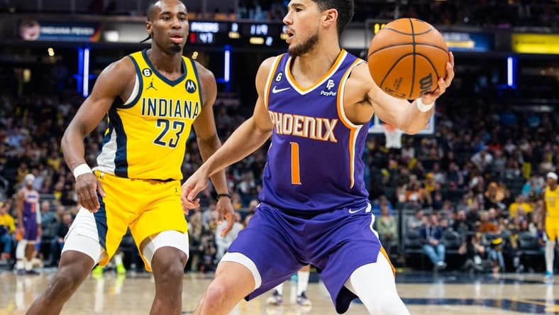 Feb 10, 2023; Indianapolis, Indiana, USA; Phoenix Suns guard Devin Booker (1) passes the ball while Indiana Pacers forward Aaron Nesmith (23) defends in the second quarter at Gainbridge Fieldhouse. Mandatory Credit: Trevor Ruszkowski-USA TODAY Sports