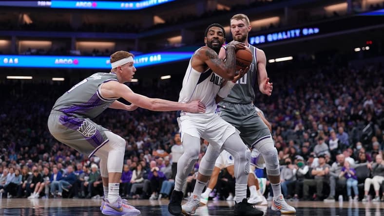 Feb 10, 2023; Sacramento, California, USA; Dallas Mavericks guard Kyrie Irving (2) holds onto a rebound between Sacramento Kings guard Kevin Huerter (9) and forward Domantas Sabonis (10) in the second quarter at the Golden 1 Center. Mandatory Credit: Cary Edmondson-USA TODAY Sports