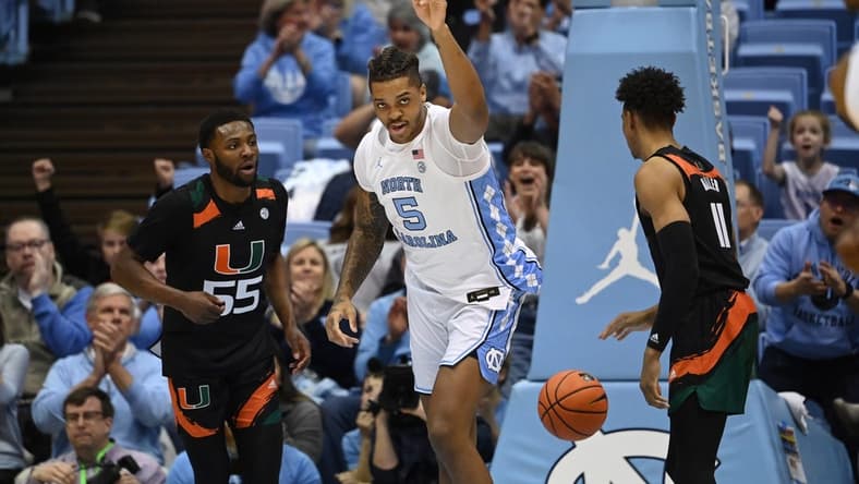 Feb 13, 2023; Chapel Hill, North Carolina, USA; North Carolina Tar Heels forward Armando Bacot (5) reacts as Miami (Fl) Hurricanes guard Wooga Poplar (55) and guard Jordan Miller (11) look on in the first half at Dean E. Smith Center. Mandatory Credit: Bob Donnan-USA TODAY Sports