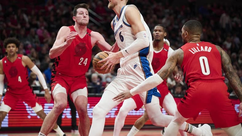 Feb 14, 2023; Portland, Oregon, USA; Washington Wizards center Kristaps Porzingis (6) drives to the basket during the first half against Portland Trail Blazers forward Drew Eubanks (24) and guard Damian Lillard (0) at Moda Center. Mandatory Credit: Troy Wayrynen-USA TODAY Sports