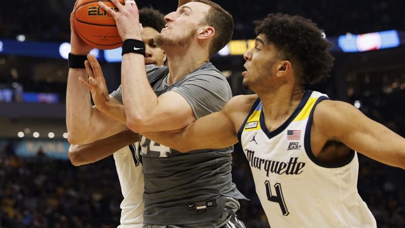 Feb 15, 2023; Milwaukee, Wisconsin, USA; Xavier Musketeers forward Jack Nunge (24) drives for the basket between Marquette Golden Eagles forward Oso Ighodaro (13) and guard Stevie Mitchell (4) during the first half at Fiserv Forum. Mandatory Credit: Jeff Hanisch-USA TODAY Sports