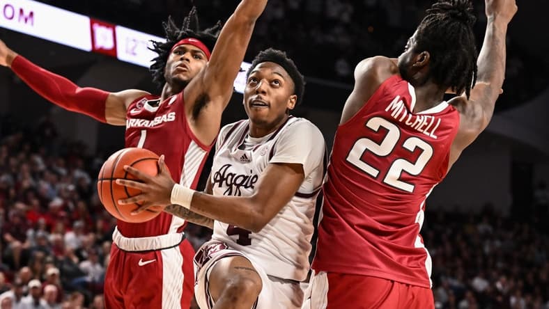 Feb 15, 2023; College Station, Texas, USA; Texas A&M Aggies guard Wade Taylor IV (4) drives through Arkansas Razorbacks guard Ricky Council IV (1) and forward Makhel Mitchell (22) during the second half at Reed Arena. Mandatory Credit: Maria Lysaker-USA TODAY Sports