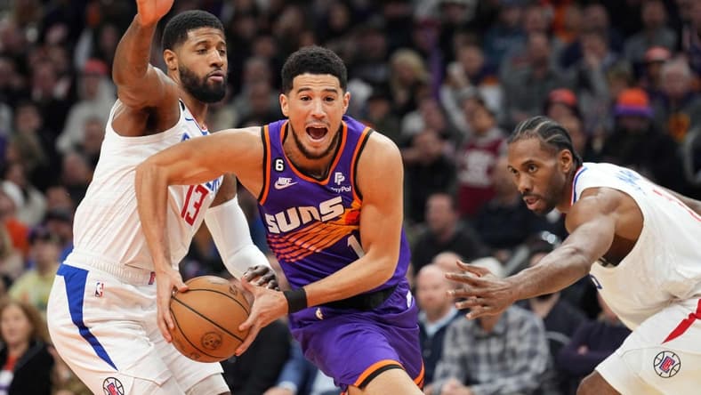 Feb 16, 2023; Phoenix, Arizona, USA; Phoenix Suns guard Devin Booker (1) drives by LA Clippers forward Paul George (13) and LA Clippers forward Kawhi Leonard (2) during the first half at Footprint Center. Mandatory Credit: Joe Camporeale-USA TODAY Sports