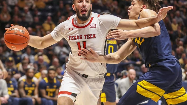 Feb 18, 2023; Morgantown, West Virginia, USA; Texas Tech Red Raiders forward Fardaws Aimaq (11) drives against West Virginia Mountaineers forward James Okonkwo (32) during the first half at WVU Coliseum. Mandatory Credit: Ben Queen-USA TODAY Sports