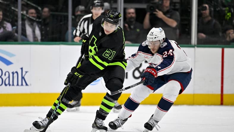 Feb 18, 2023; Dallas, Texas, USA; Dallas Stars left wing Jason Robertson (21) keeps the puck away from Columbus Blue Jackets right wing Mathieu Olivier (24) during the first period at the American Airlines Center. Mandatory Credit: Jerome Miron-USA TODAY Sports