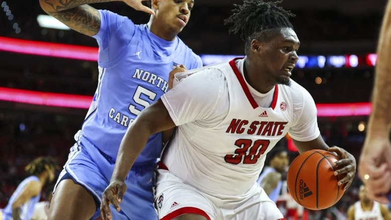 Feb 19, 2023; Raleigh, North Carolina, USA;  North Carolina State Wolfpack forward D.J. Burns Jr. (30) maintains possession against North Carolina Tar Heels forward Armando Bacot (5) during the first half of the game at PNC Arena. Mandatory Credit: Jaylynn Nash-USA TODAY Sports
