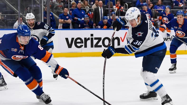 Feb 22, 2023; Elmont, New York, USA; Winnipeg Jets center Morgan Barron (36) attempts a shot defended by New York Islanders defenseman Noah Dobson (8) during the third period at UBS Arena. Mandatory Credit: Dennis Schneidler-USA TODAY Sports