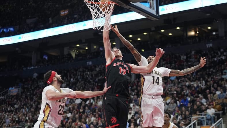 Feb 23, 2023; Toronto, Ontario, CAN; Toronto Raptors center Jakob Poeltl (19) tips in a ball against New Orleans Pelicans forward Brandon Ingram (14) and  forward Larry Nance Jr. (22) during the first half at Scotiabank Arena. Mandatory Credit: John E. Sokolowski-USA TODAY Sports