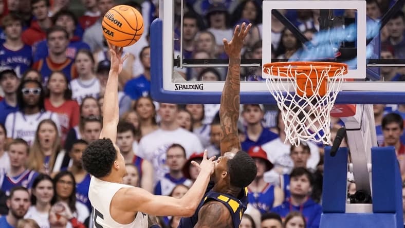 Feb 25, 2023; Lawrence, Kansas, USA; Kansas Jayhawks guard Kevin McCullar Jr. (15) shoots as West Virginia Mountaineers forward Jimmy Bell Jr. (15) defends during the first half at Allen Fieldhouse. Mandatory Credit: Denny Medley-USA TODAY Sports