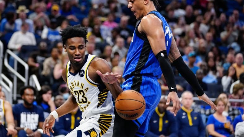 Feb 25, 2023; Orlando, Florida, USA; Indiana Pacers forward Aaron Nesmith (23) dribbles the ball against Orlando Magic forward Paolo Banchero (5) during the second quarter at Amway Center. Mandatory Credit: Rich Storry-USA TODAY Sports