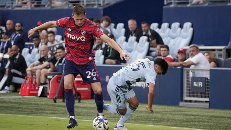 May 10, 2022; Kansas City, Kansas, USA; FC Dallas defender Lucas Bartlett (26) and Sporting Kansas City midfielder Ozzie Cisneros (25) fight for the ball during the first half at Children's Mercy Park. Mandatory Credit: Denny Medley-USA TODAY Sports