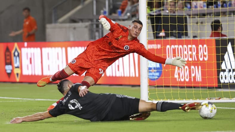 Sep 13, 2022; Houston, Texas, USA; New England Revolution goalkeeper Djordje Petrovic (99) leaps to make a save as Houston Dynamo FC forward Sebastian Ferreira (9) attempts to score during the second half at PNC Stadium. Mandatory Credit: Troy Taormina-USA TODAY Sports