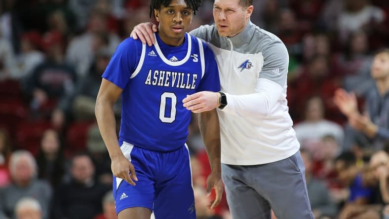 Dec 21, 2022; Fayetteville, Arkansas, USA; UNC Asheville Bulldogs guard Trent Stephney (0) talks to head coach Mike Morrell during the first half against the Arkansas Razorbacks at Bud Walton Arena. Mandatory Credit: Nelson Chenault-USA TODAY Sports