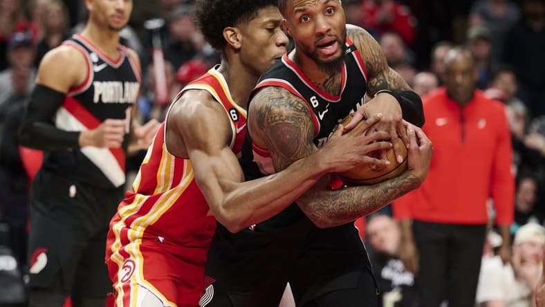 Jan 30, 2023; Portland, Oregon, USA; Atlanta Hawks forward De'Andre Hunter (12) fouls Portland Trail Blazers guard Damian Lillard (0) during the second half at Moda Center. Mandatory Credit: Troy Wayrynen-USA TODAY Sports