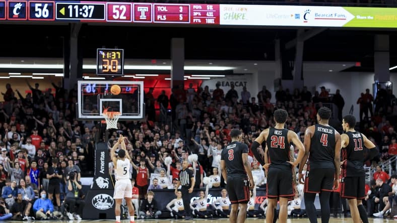 Feb 22, 2023; Cincinnati, Ohio, USA; Members of the Temple Owls stand on the court as Cincinnati Bearcats guard David DeJulius (5) shoots a technical free throw in the second half at Fifth Third Arena. Mandatory Credit: Aaron Doster-USA TODAY Sports