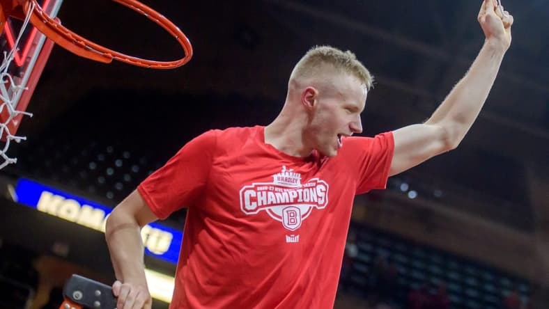 Bradley's Rienk Mast holds up a piece of net he cut in celebration of the Braves' MVC championship after defeating Drake 73-61on Sunday, Feb. 26, 2023 at Carver Arena.