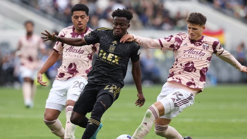 Mar 4, 2023; Los Angeles, California, USA; Los Angeles FC forward Kwadwo Opoku (22) is challenged from behind by Portland Timbers defender Justin Rasmussen (14) during the second half at BMO Stadium. Mandatory Credit: Jason Parkhurst-USA TODAY Sports