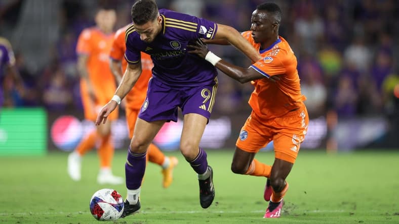 Mar 4, 2023; Orlando, Florida, USA; Orlando City forward Ercan Kara (9) is tackled by FC Cincinnati midfielder Obinna Nwobodo (5) at Exploria Stadium. Mandatory Credit: Nathan Ray Seebeck-USA TODAY Sports