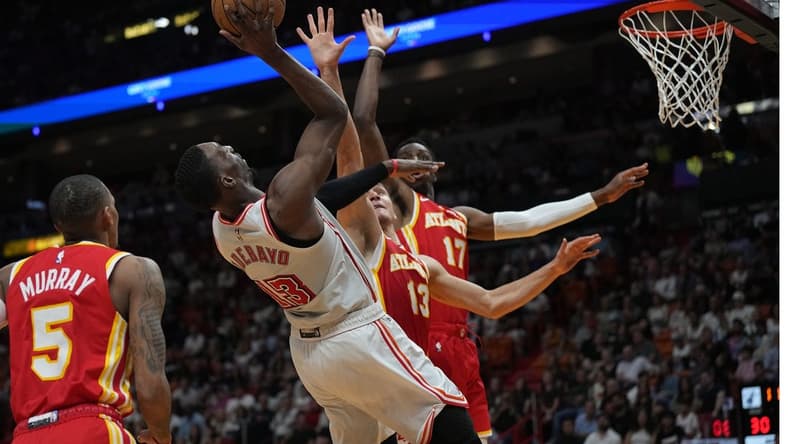 Mar 4, 2023; Miami, Florida, USA; Miami Heat center Bam Adebayo (13) takes an off balance shot as Atlanta Hawks guard Bogdan Bogdanovic (13) defends in the first half at Miami-Dade Arena. Mandatory Credit: Jim Rassol-USA TODAY Sports
