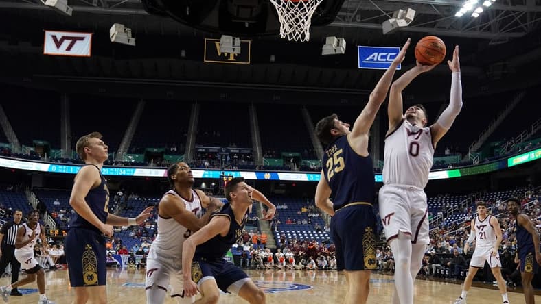 Mar 7, 2023; Greensboro, NC, USA; Virginia Tech Hokies guard Hunter Cattoor (0) takes a shot over Notre Dame Fighting Irish forward Matt Zona (25) during the first half of the first round of the ACC tournament at Greensboro Coliseum. Mandatory Credit: John David Mercer-USA TODAY Sports