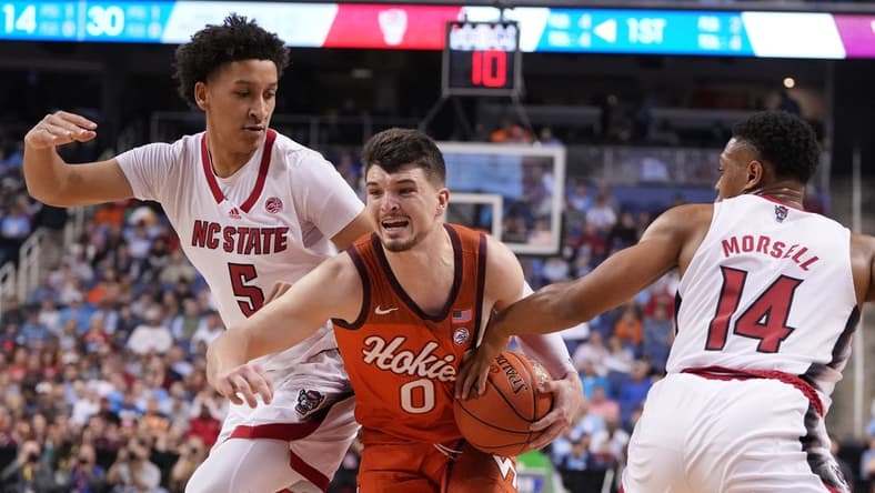 Mar 8, 2023; Greensboro, NC, USA; Virginia Tech Hokies guard Hunter Cattoor (0) with the ball as North Carolina State Wolfpack guard Jack Clark (5) and guard Casey Morsell (14) defend in the first half of the second round at Greensboro Coliseum. Mandatory Credit: Bob Donnan-USA TODAY Sports