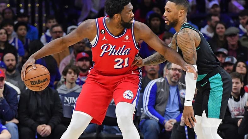 Mar 10, 2023; Philadelphia, Pennsylvania, USA; Philadelphia 76ers center Joel Embiid (21) is defended by Portland Trail Blazers guard Damian Lillard (0) during the first quarter at Wells Fargo Center. Mandatory Credit: Eric Hartline-USA TODAY Sports