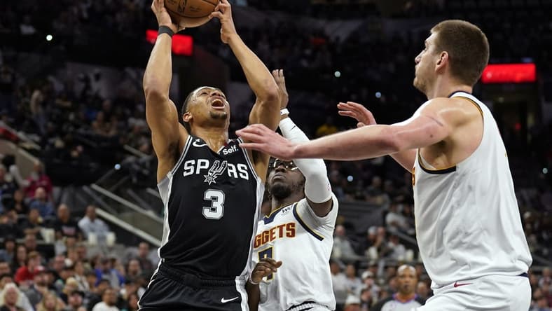 Mar 10, 2023; San Antonio, Texas, USA; San Antonio Spurs forward Keldon Johnson (3) drives to the basket against Denver Nuggets guard Reggie Jackson (7) and center Nikola Jokic (15) during the first half at AT&T Center. Mandatory Credit: Scott Wachter-USA TODAY Sports