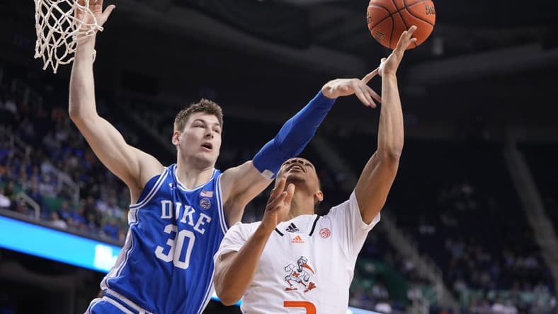Mar 10, 2023; Greensboro, NC, USA; Miami (Fl) Hurricanes guard Isaiah Wong (2) shoots as Duke Blue Devils center Kyle Filipowski (30) defends in the second half during the semifinals of the ACC Tournament at Greensboro Coliseum. Mandatory Credit: Bob Donnan-USA TODAY Sports