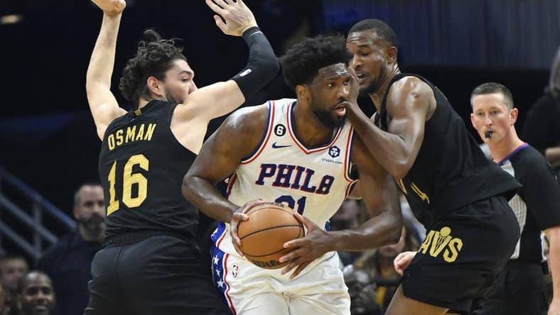 Mar 15, 2023; Cleveland, Ohio, USA; Philadelphia 76ers center Joel Embiid (21) looks to pass while defended by Cleveland Cavaliers forward Cedi Osman (16) and forward Evan Mobley (4) in the second quarter at Rocket Mortgage FieldHouse. Mandatory Credit: David Richard-USA TODAY Sports
