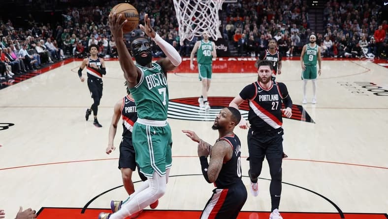 Mar 17, 2023; Portland, Oregon, USA; dBoston Celtics shooting guard Jaylen Brown (7) shoots the ball against Portland Trail Blazers point guard Damian Lillard (0) uring the first half at Moda Center. Mandatory Credit: Soobum Im-USA TODAY Sports