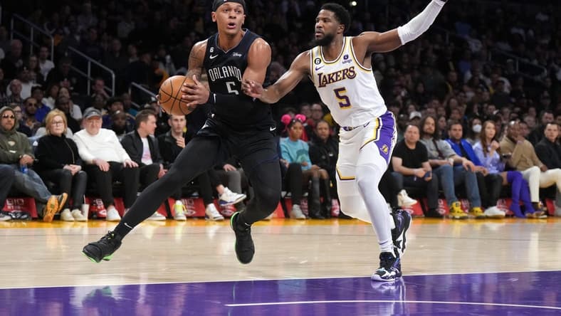 Mar 19, 2023; Los Angeles, California, USA; Orlando Magic forward Paolo Banchero (left) dribbles the ball against Los Angeles Lakers guard Malik Beasley in the first half at Crypto.com Arena. Mandatory Credit: Kirby Lee-USA TODAY Sports